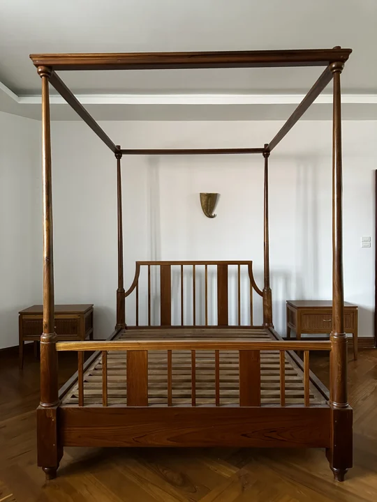 A handmade hardwood four-poster bed frame with bedside cabinets