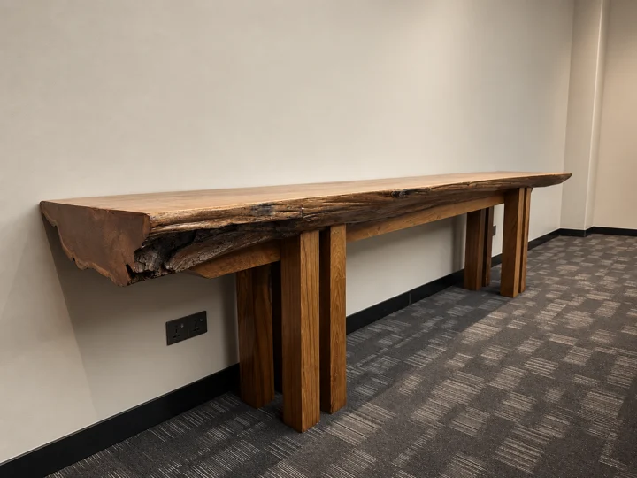 A substantial live-edge hardwood console with its natural grain and irregular edge